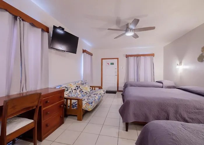 Wide view of a guest room with multiple beds, tiled floor, seating, and a desk